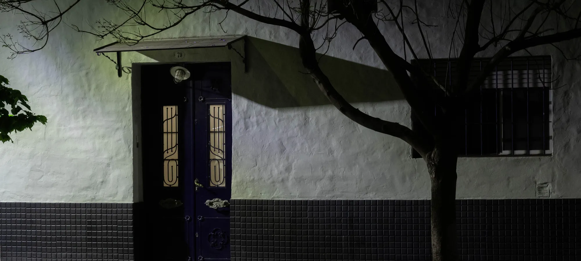 Une porte d’immeuble éclairée dans la nuit.